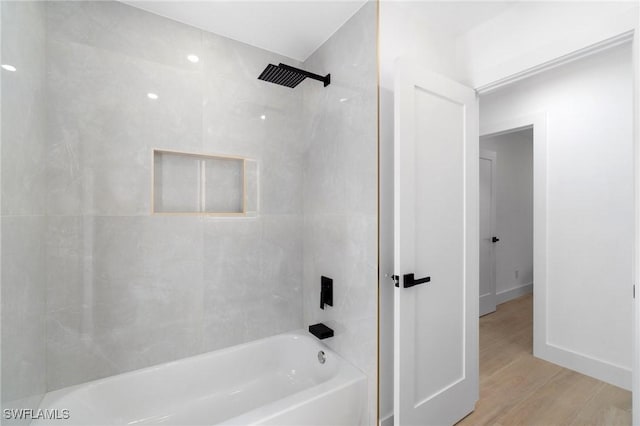 bathroom featuring  shower combination, wood finished floors, and baseboards