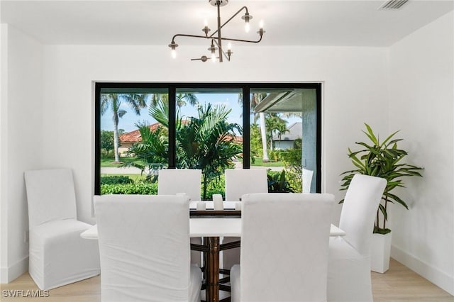 dining room featuring a chandelier, baseboards, and light wood finished floors