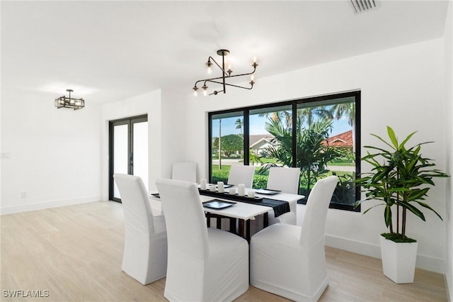 dining space with light wood finished floors, visible vents, and a notable chandelier