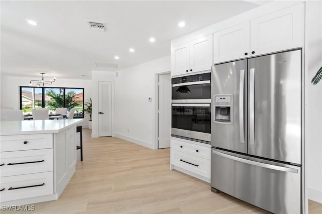 kitchen featuring stainless steel appliances, light countertops, visible vents, white cabinets, and light wood-type flooring