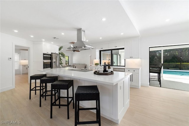 kitchen with black appliances, white cabinetry, island range hood, and light countertops