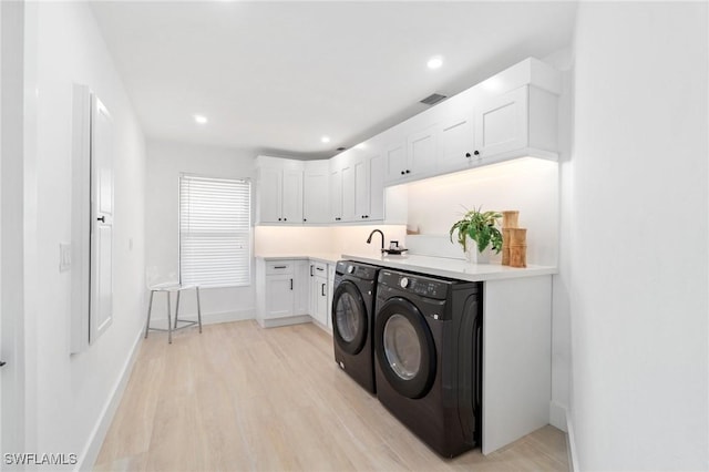 laundry room featuring cabinet space, light wood finished floors, baseboards, washing machine and clothes dryer, and recessed lighting