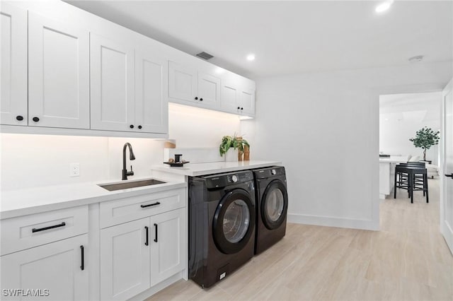 washroom with baseboards, washing machine and clothes dryer, light wood-type flooring, a sink, and recessed lighting