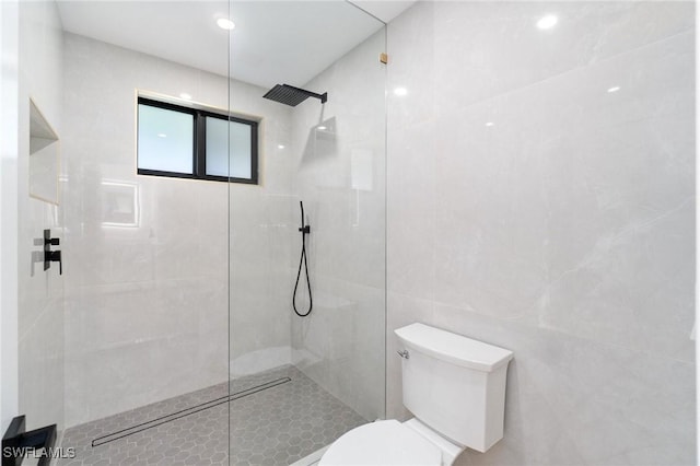 full bathroom with tile walls, toilet, and a walk in shower