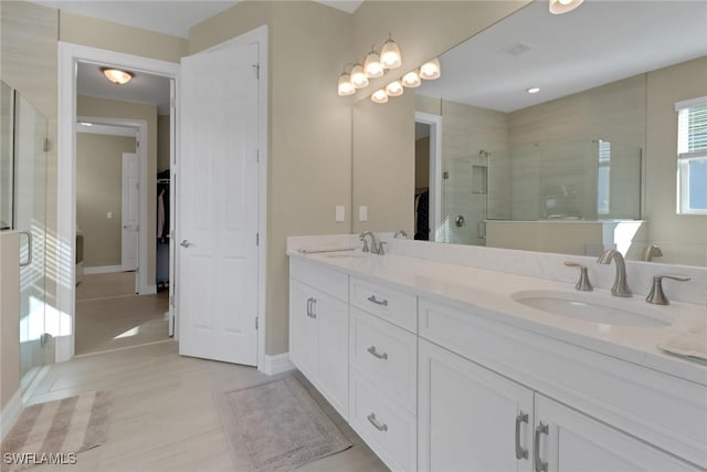 bathroom featuring double vanity, a shower stall, a spacious closet, and a sink