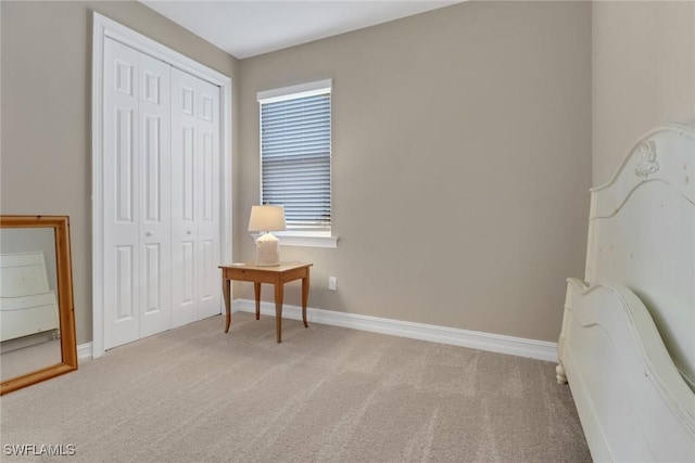 bedroom featuring light carpet, baseboards, and a closet