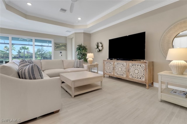 living area with ceiling fan, a tray ceiling, visible vents, and baseboards