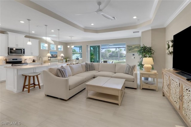 living room with recessed lighting, a raised ceiling, and crown molding