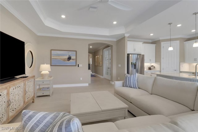 living area featuring recessed lighting, arched walkways, a raised ceiling, and ornamental molding