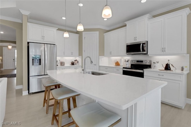 kitchen featuring appliances with stainless steel finishes, white cabinets, light countertops, and a sink