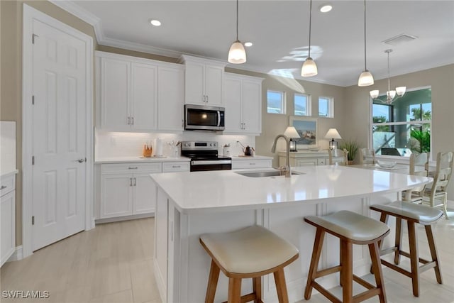 kitchen with appliances with stainless steel finishes, a sink, a kitchen island with sink, and white cabinetry