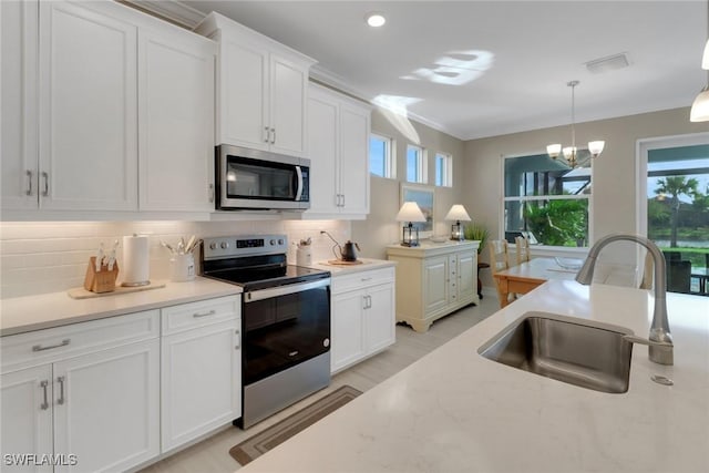 kitchen featuring white cabinets, pendant lighting, stainless steel appliances, and a sink