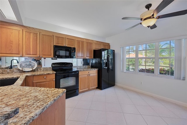 kitchen featuring brown cabinets, black appliances, light tile patterned floors, baseboards, and light stone countertops