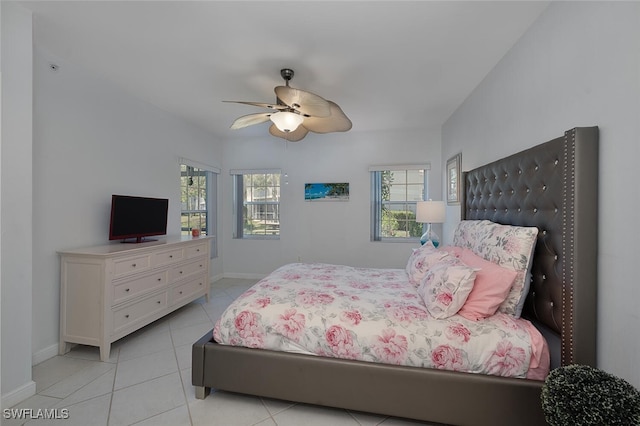 bedroom featuring light tile patterned floors, ceiling fan, multiple windows, and baseboards