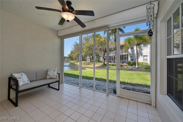 sunroom / solarium featuring a water view and a ceiling fan