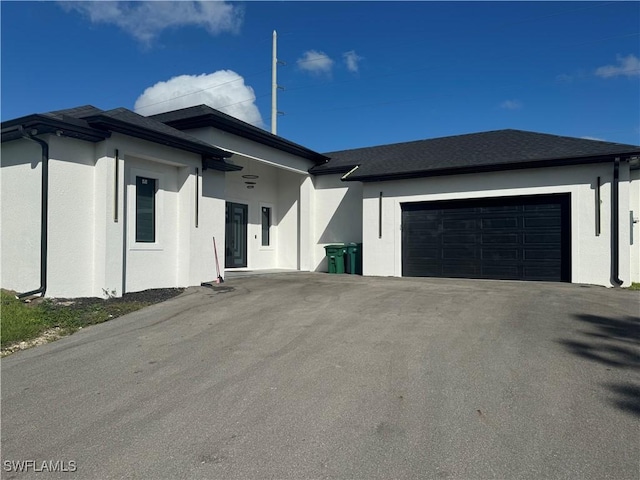 view of front of property with an attached garage, roof with shingles, aphalt driveway, and stucco siding