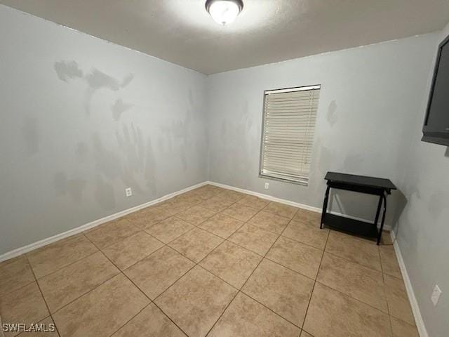 empty room with baseboards and light tile patterned floors