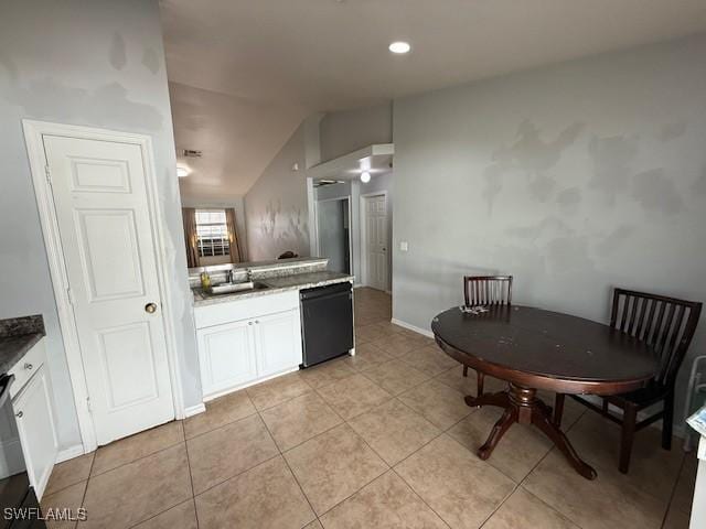 kitchen featuring light tile patterned floors, white cabinets, dishwasher, lofted ceiling, and a sink