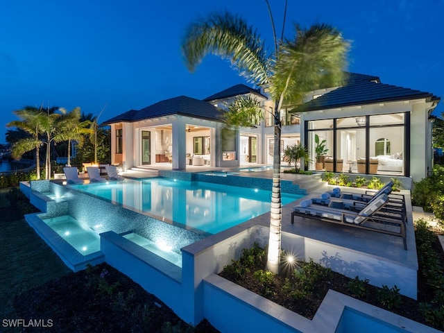 view of pool with an infinity pool, a hot tub, and a patio