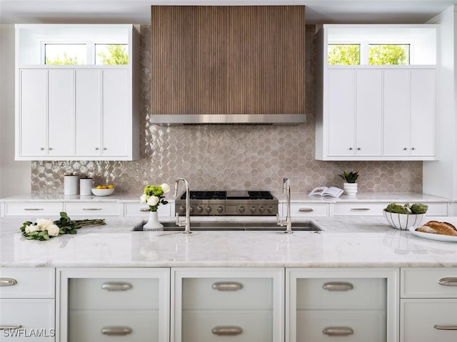 kitchen featuring light stone counters, white cabinets, range, and decorative backsplash