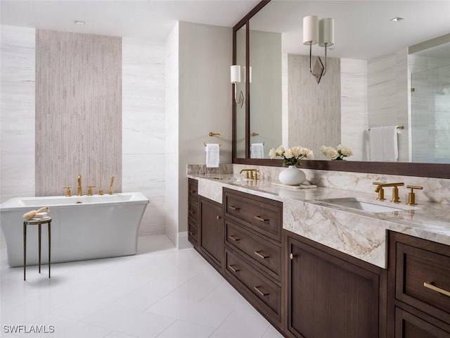 bathroom with double vanity, a soaking tub, a sink, a shower stall, and tile walls