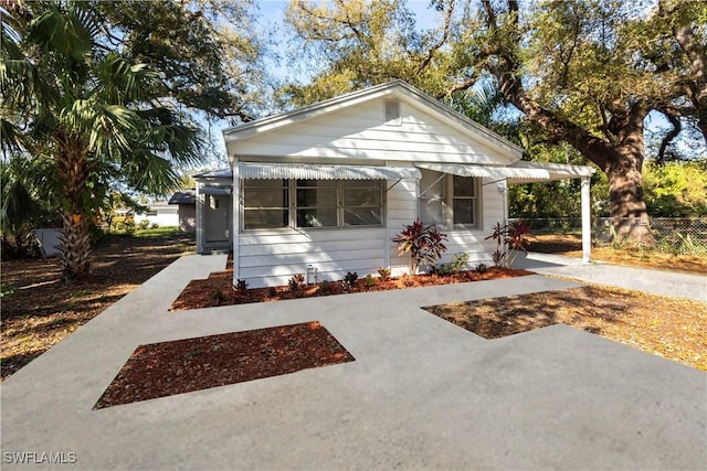 bungalow-style home featuring a carport, fence, and concrete driveway