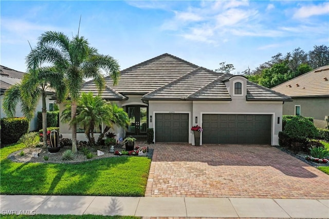 view of front of property with a tiled roof, decorative driveway, an attached garage, and stucco siding