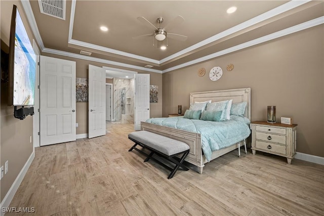 bedroom with visible vents, baseboards, a raised ceiling, light wood-style flooring, and crown molding