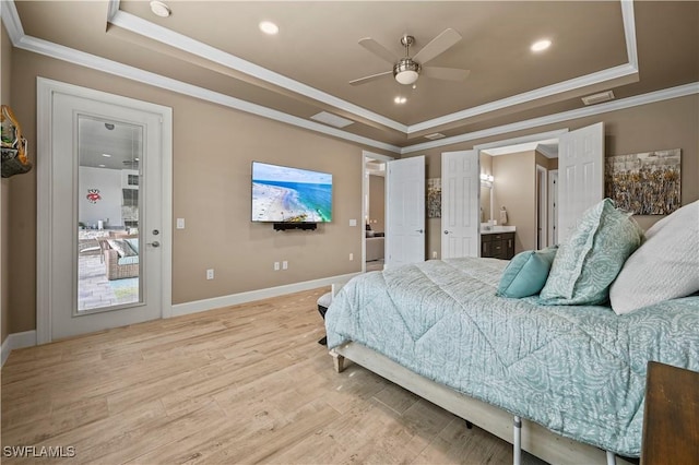 bedroom with baseboards, a tray ceiling, light wood-type flooring, and crown molding