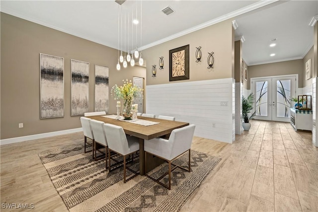 dining space with light wood-style floors, french doors, ornamental molding, and baseboards