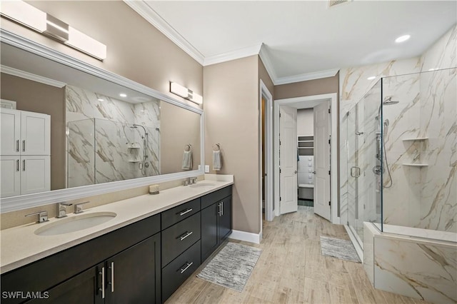 bathroom featuring a spacious closet, a sink, a marble finish shower, and crown molding