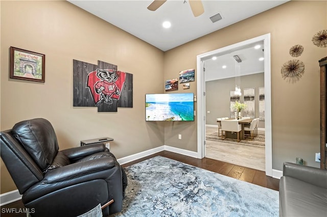 sitting room with dark wood-style floors, baseboards, visible vents, and a ceiling fan