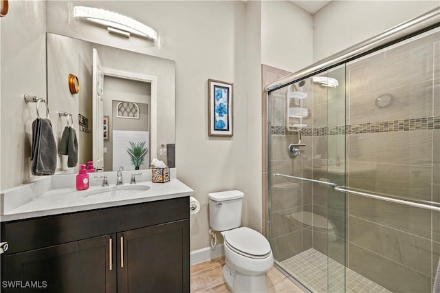 bathroom with toilet, a shower stall, baseboards, and vanity