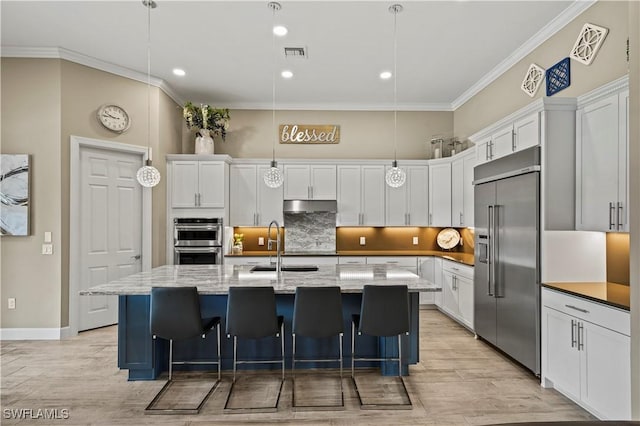 kitchen featuring a kitchen island with sink, visible vents, appliances with stainless steel finishes, dark stone counters, and pendant lighting