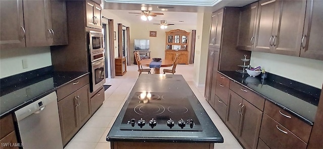 kitchen with appliances with stainless steel finishes, dark stone counters, and dark brown cabinetry