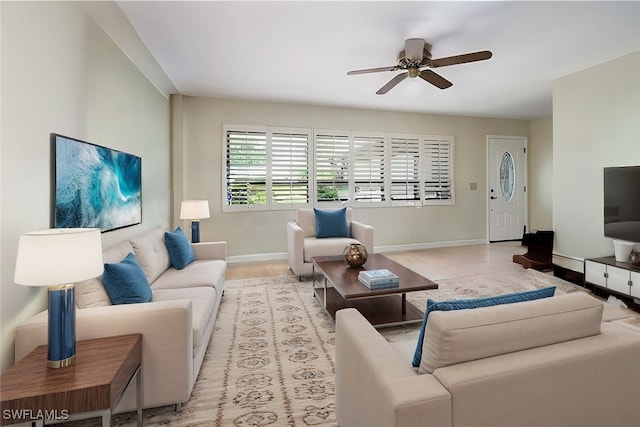 living area with ceiling fan and baseboards