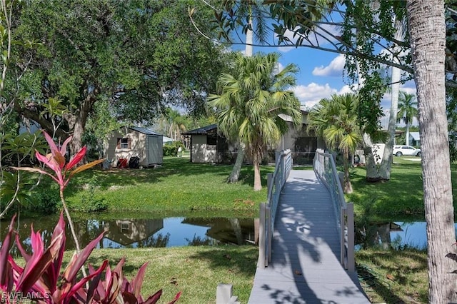 view of yard featuring a water view, a storage shed, and an outbuilding