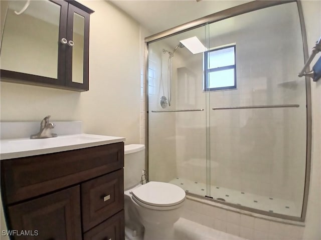 bathroom featuring toilet, a stall shower, and vanity