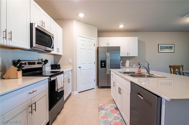 kitchen with stainless steel appliances, a sink, white cabinetry, light countertops, and an island with sink