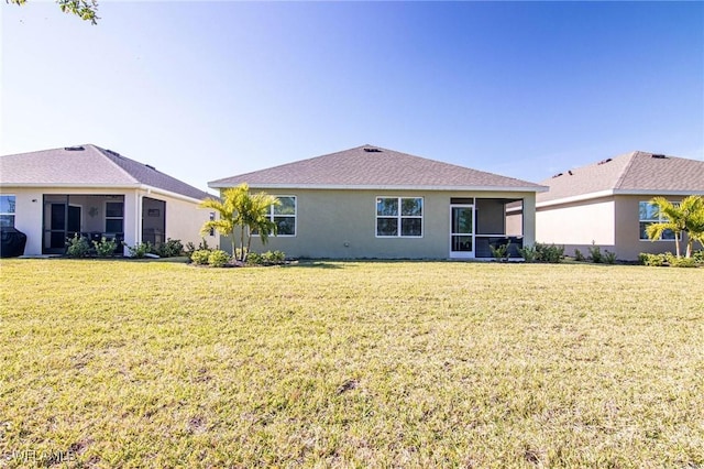 rear view of property with a sunroom, a lawn, and stucco siding