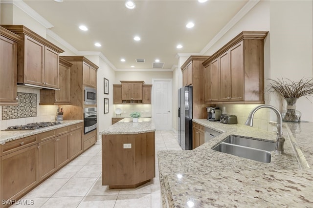 kitchen with light stone countertops, a kitchen island, stainless steel appliances, and a sink