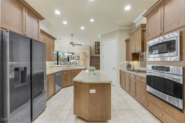 kitchen with light tile patterned floors, a kitchen island, ornamental molding, light stone countertops, and stainless steel appliances