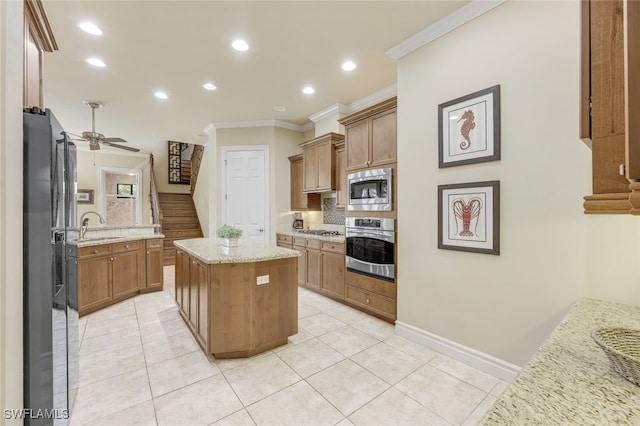 kitchen with brown cabinets, light stone countertops, a kitchen island, and stainless steel appliances