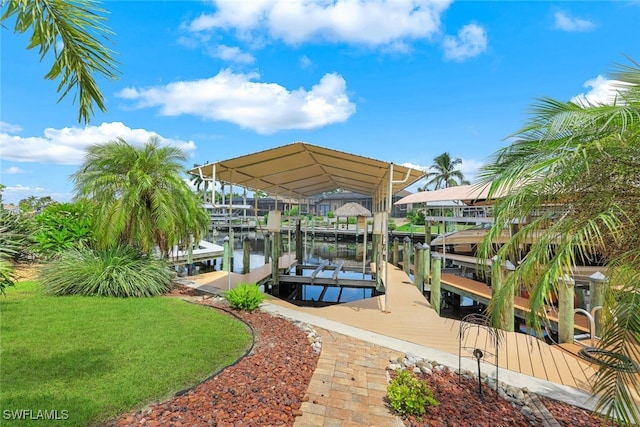 view of dock with a water view, boat lift, and a yard