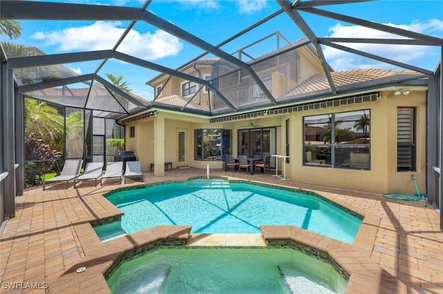 view of swimming pool with a pool with connected hot tub, a patio, a lanai, and a ceiling fan