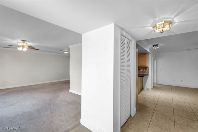 hallway with light tile patterned floors, baseboards, visible vents, and light colored carpet