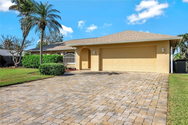 ranch-style home with a garage, cooling unit, decorative driveway, a front lawn, and stucco siding