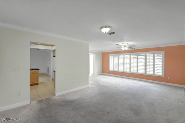 spare room featuring crown molding, baseboards, and light colored carpet