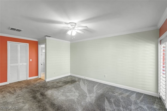 carpeted spare room featuring baseboards, a ceiling fan, visible vents, and crown molding