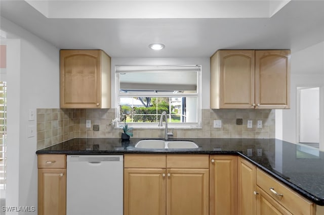 kitchen with tasteful backsplash, dishwasher, dark stone countertops, light brown cabinetry, and a sink